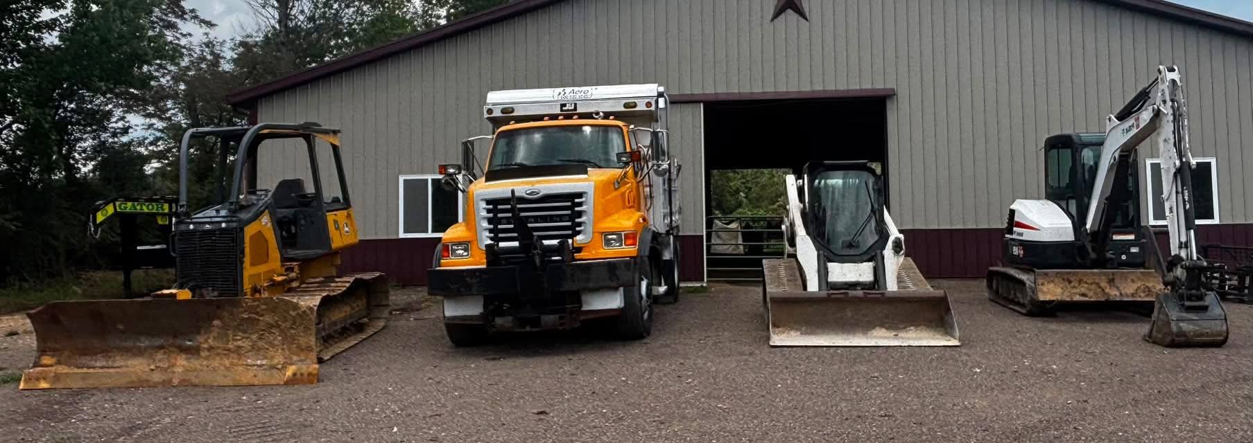 Funk Excavating equipment lineup including a dozer, dump truck, skid steer and mini excavator in front of the shop