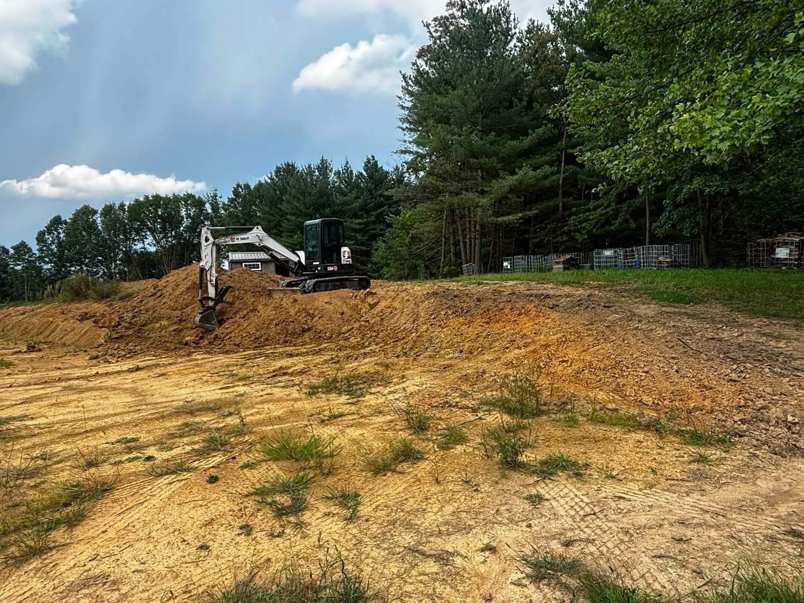 Mini excavator actively grading a dirt mound on a Carrollton, Ohio job site
